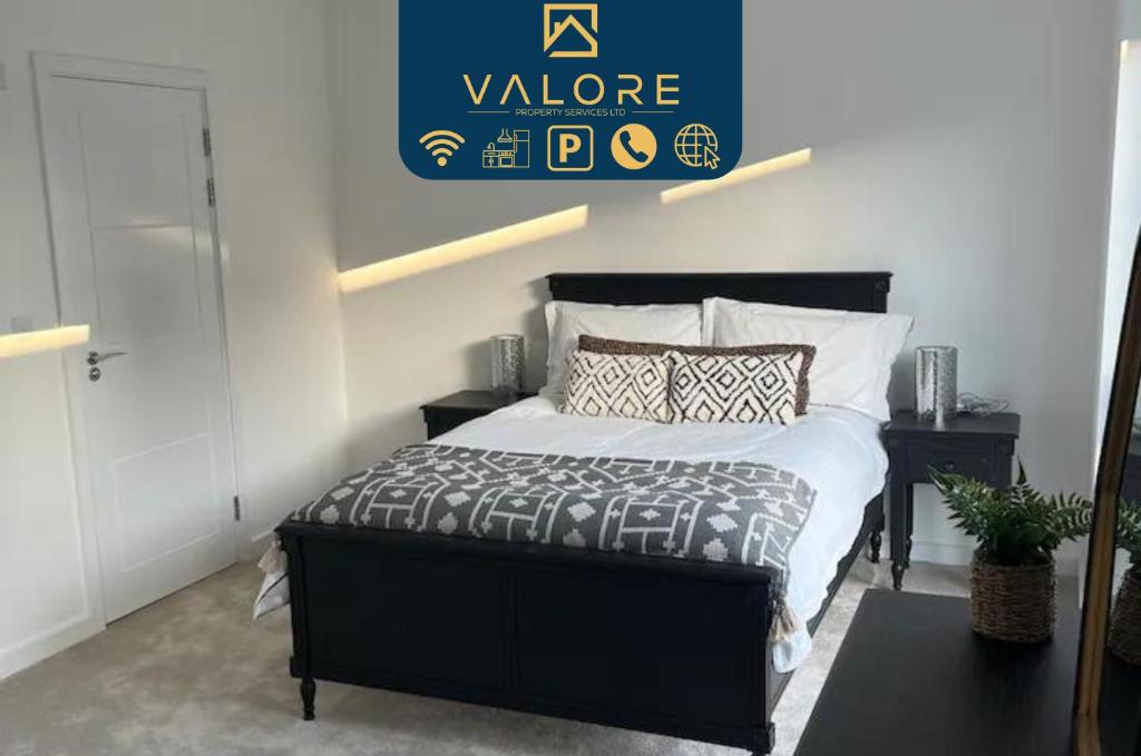 a bedroom with a bed with a black bed frame at Outstanding 4-Bedroom Town House By Valore Property Services in Milton Keynes