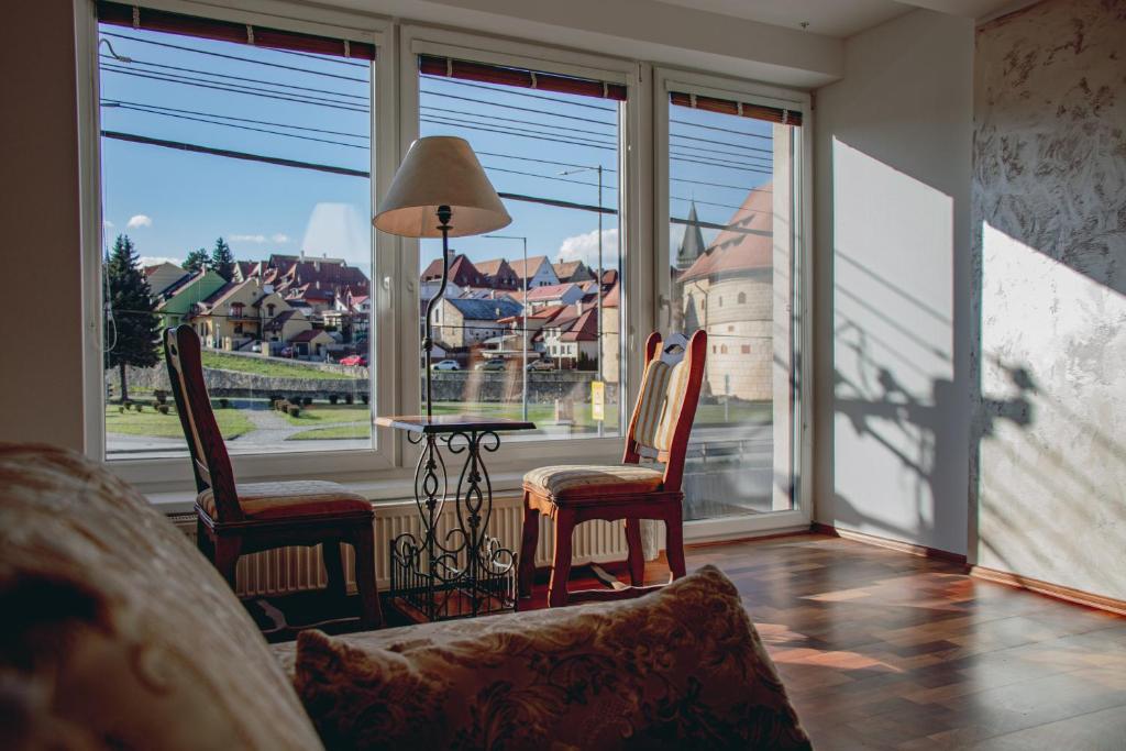 a living room with a table and chairs and a large window at Contact Apartman in Bardejov