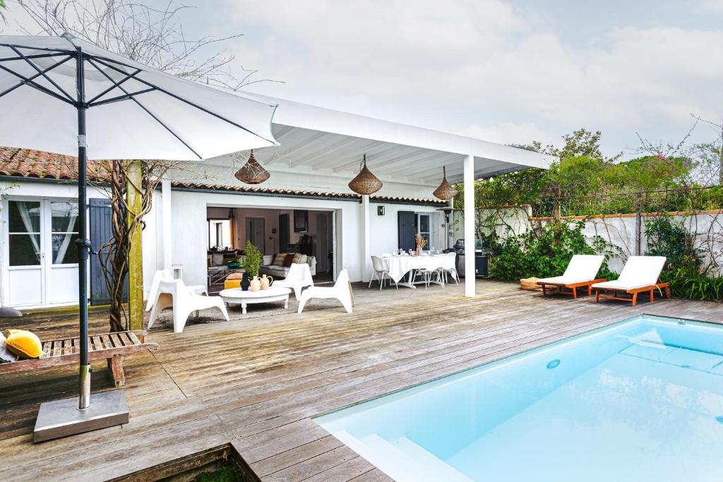 un patio extérieur avec une piscine et un parasol dans l'établissement Maison de charme La Flotte en Ré, à La Flotte