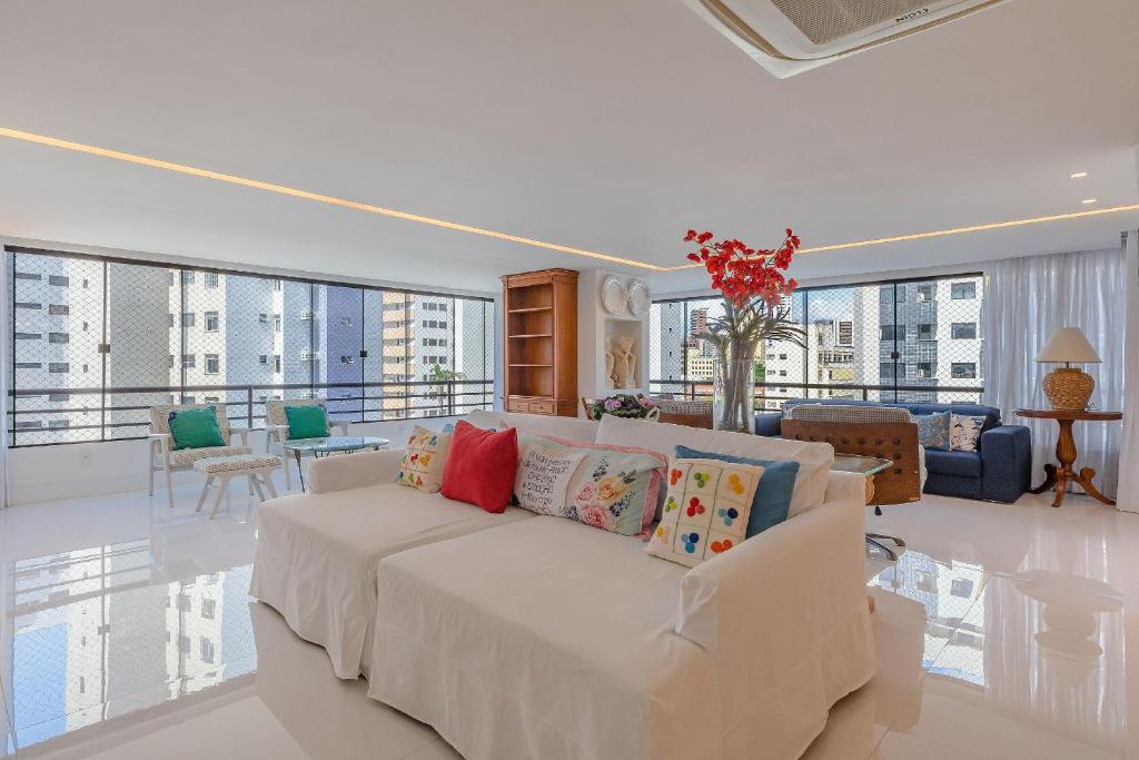 uma sala de estar com um sofá branco com almofadas coloridas em Condomínio Mykonos #400 - Apê Deluxe em Fortaleza por Carpediem em Fortaleza
