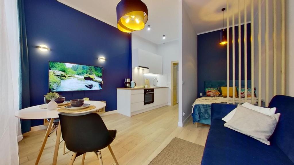 a living room with blue walls and a table and a bed at Uroczy Apartament Leczycka 7/2A Wrocław in Wrocław