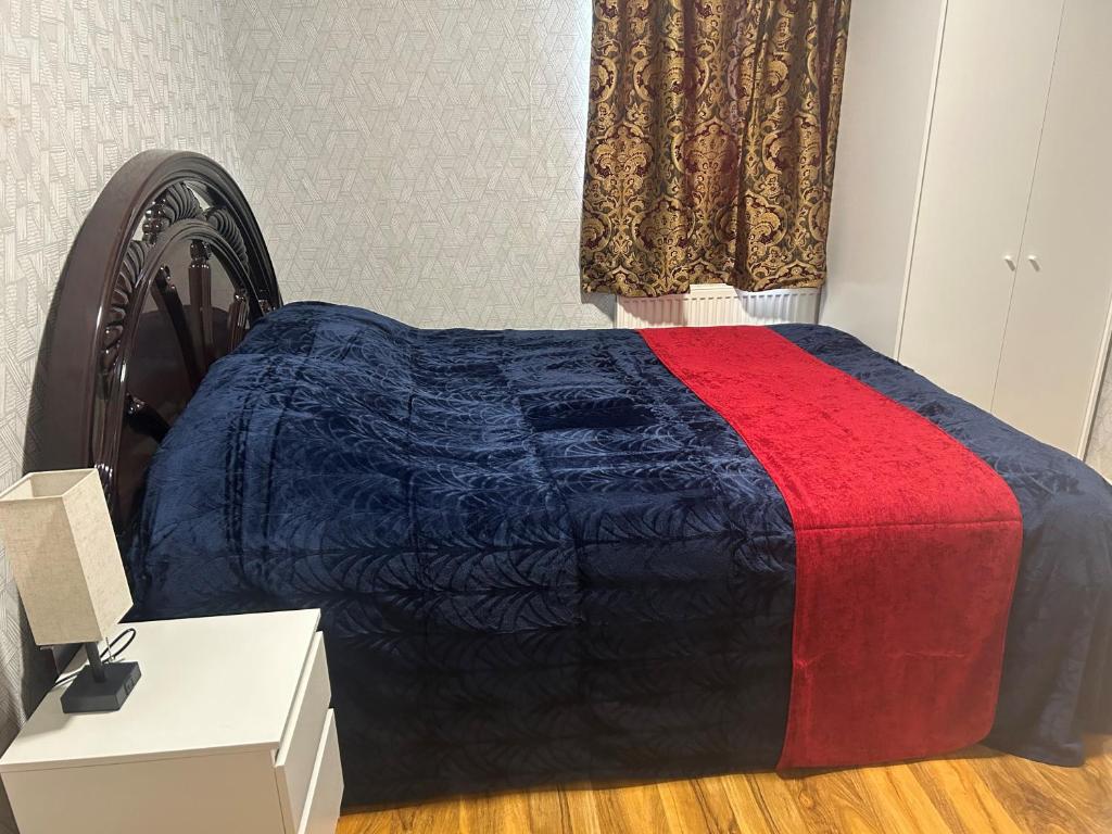 um quarto com uma cama com um cobertor azul e vermelho em London Holiday Home em Londres