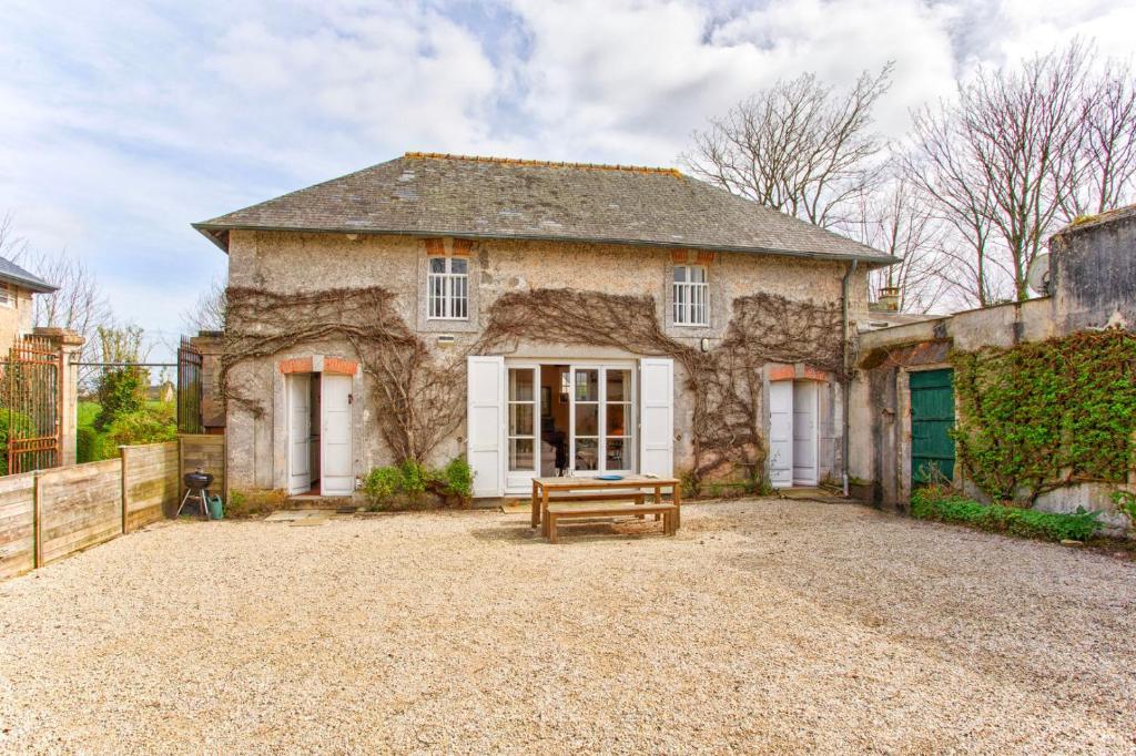 ein Steinhaus mit einer Bank davor in der Unterkunft La Rabouillère - House in Omaha Beach in Commes