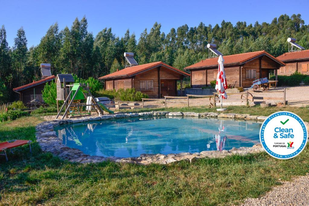 a swimming pool in front of a log cabin at Quintinha do Casal Ruivo in Figueiró dos Vinhos