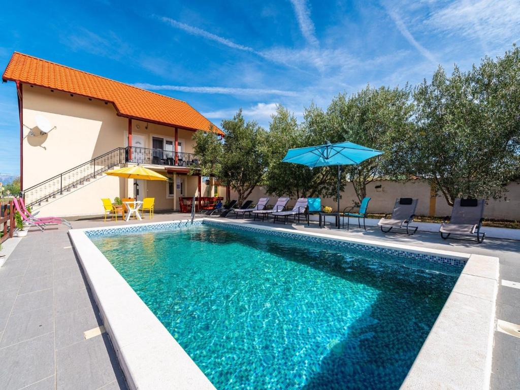 a swimming pool with chairs and a blue umbrella at Holiday Home Villa Vesna Lux in Zadar