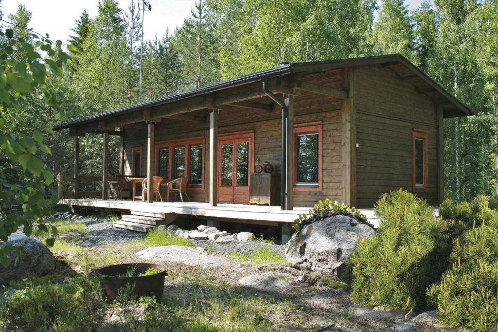 uma cabana de madeira na floresta com um alpendre em Kodikas mökki lähellä luontoa Nurmijärven Perttulassa em Nurmijärvi