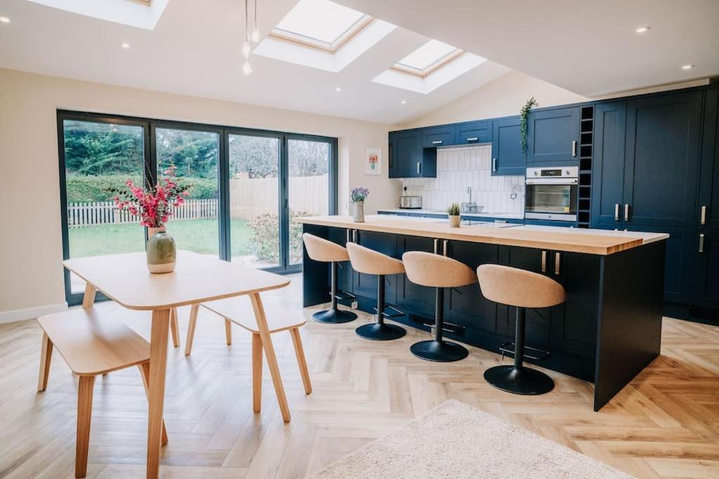 cocina con armarios azules, mesa y sillas en Modern Home in Warwickshire, en Stratford-upon-Avon