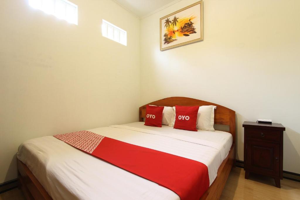 um quarto com uma cama com duas almofadas vermelhas em OYO 93789 Mbah Carik Homestay em Magelang