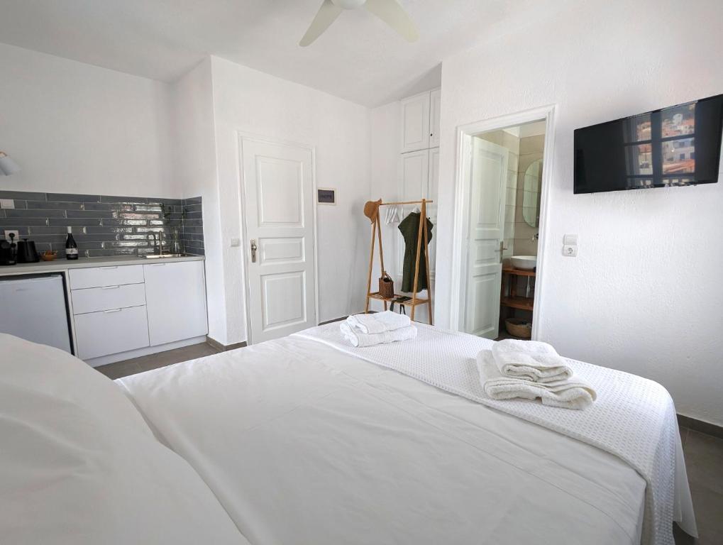 a white bedroom with a bed with towels on it at The Botanist Guesthouse in Skopelos Town