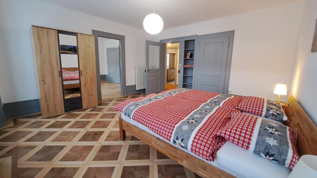 Schlafzimmer mit einem Bett mit einer roten Bettdecke in der Unterkunft Appartement de vacances Les Jardins in Saint-Imier