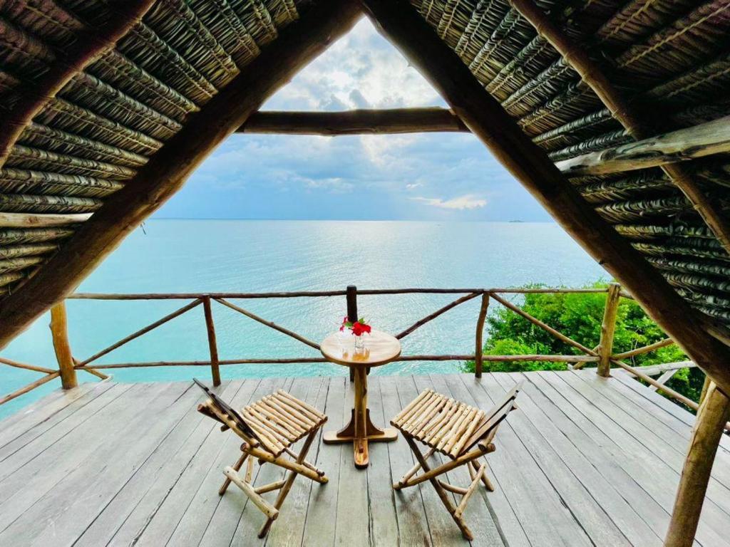 2 sillas y una mesa en una terraza con vistas al océano en Adventurevilla, en Kendwa