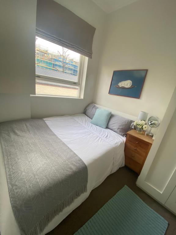 um pequeno quarto com uma cama e uma janela em Single Bedroom in Chelsea em Londres