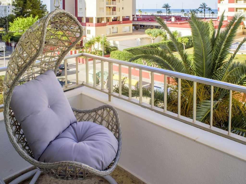 a wicker chair with a purple cushion sitting on a balcony at Apartamento gandiaziar premium in Gandía