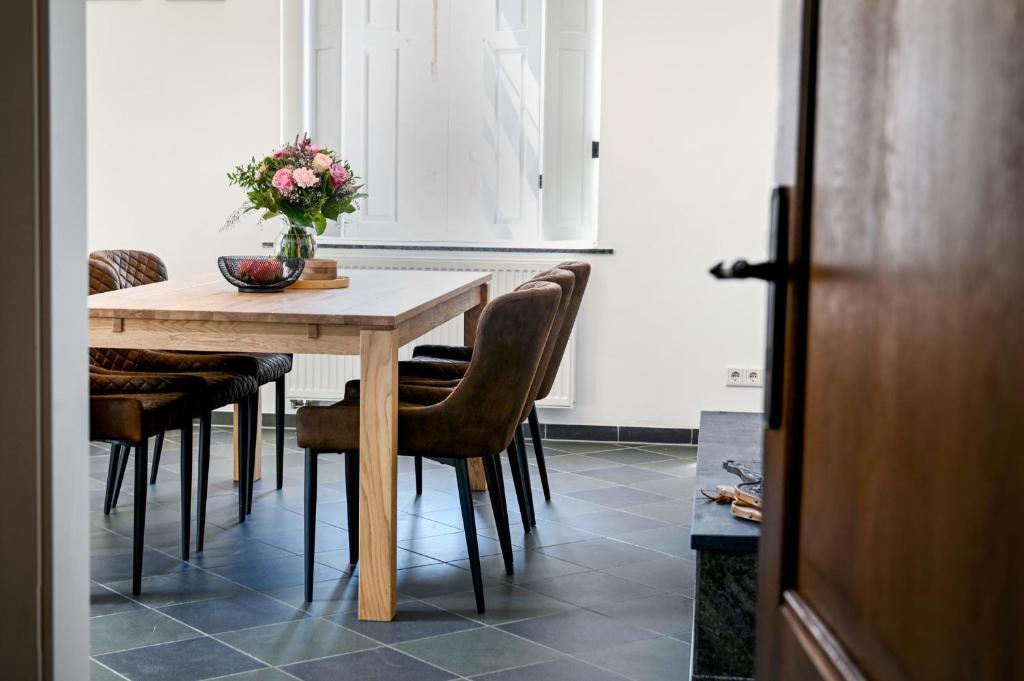 a dining room table with chairs and a vase of flowers at Römer-Apartment in Xanten