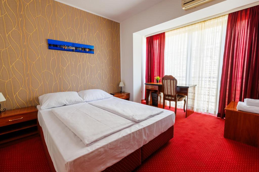 a bedroom with a bed and a desk and a table at Pansion Strossmayer in Osijek
