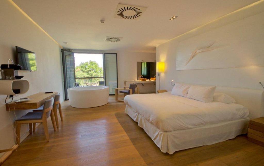 Un dormitorio con una cama y un baño con bañera. en Arantza Hotela- Adults Only, en Arantza