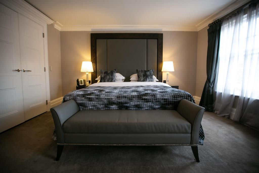 a bedroom with a bed with a couch and two lamps at One Warwick Park Hotel in Royal Tunbridge Wells