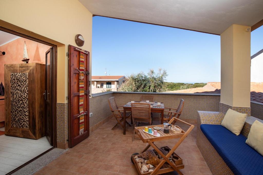 een patio met een bank en een tafel op een balkon bij Casa delle Mimose by Wonderful Italy in Badesi
