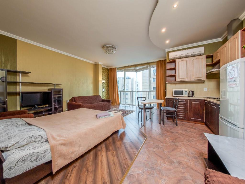 Cet appartement comprend une chambre avec un lit, un salon et une cuisine. dans l'établissement Однокомнатная квартира-студия, à Almaty