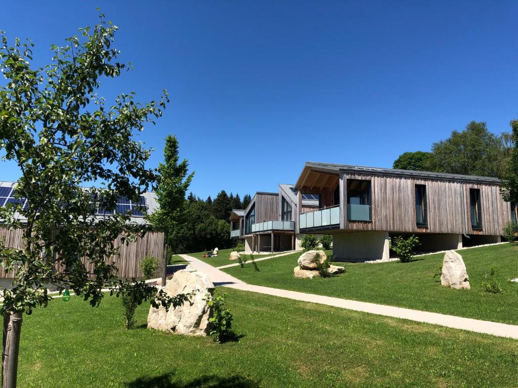 une maison dans une cour avec des rochers dans l'herbe dans l'établissement Feriendorf Waidlerland, à Mauth