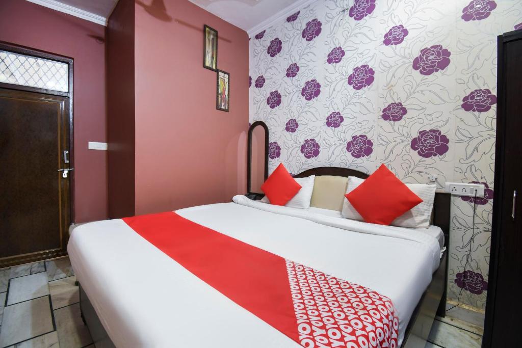 Schlafzimmer mit einem großen Bett mit roter und weißer Bettwäsche in der Unterkunft OYO Jk Mahal in Sūbedārganj