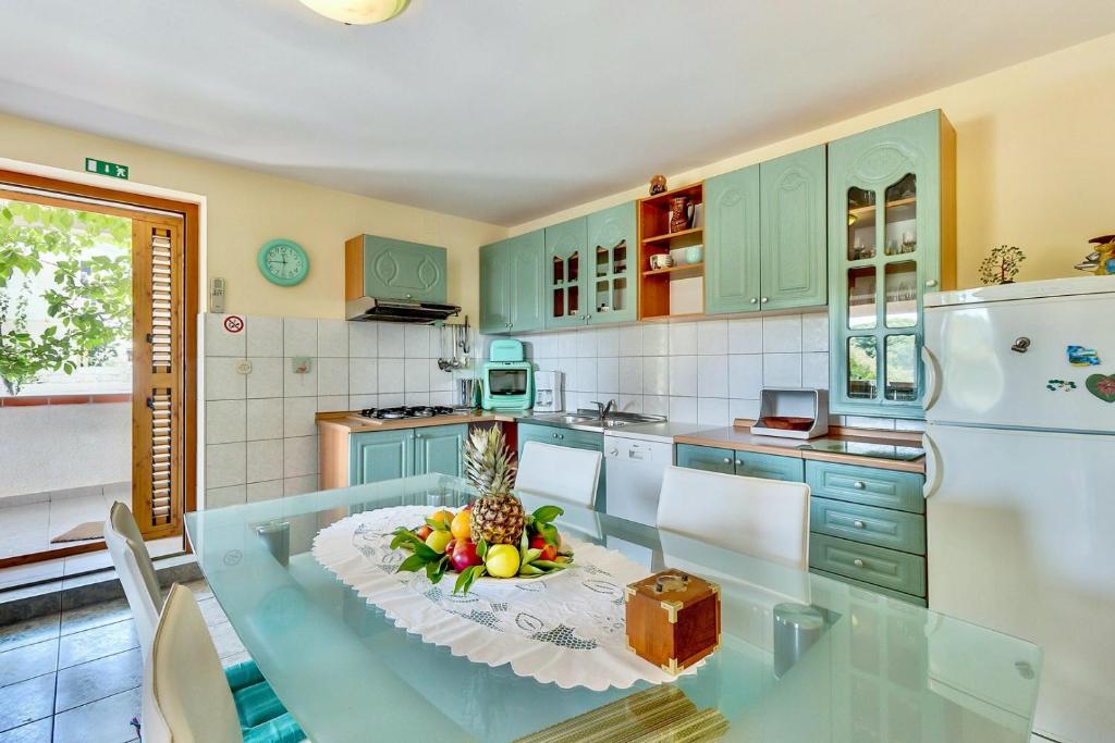 a kitchen with a table with a bowl of fruit on it at House ROSSELLA with cozy apartment and rooms close to the beach in Nerezine