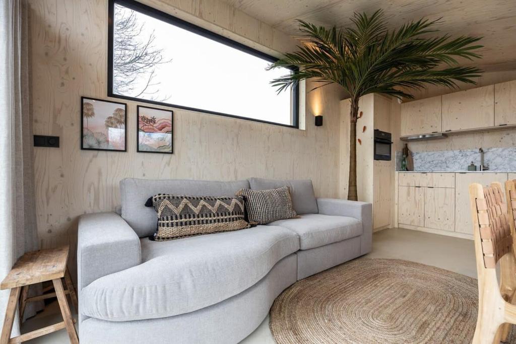 uma sala de estar com um sofá e uma palmeira em Hello Zeeland - Tiny House Zeeuwse Liefde 11 em Westkapelle