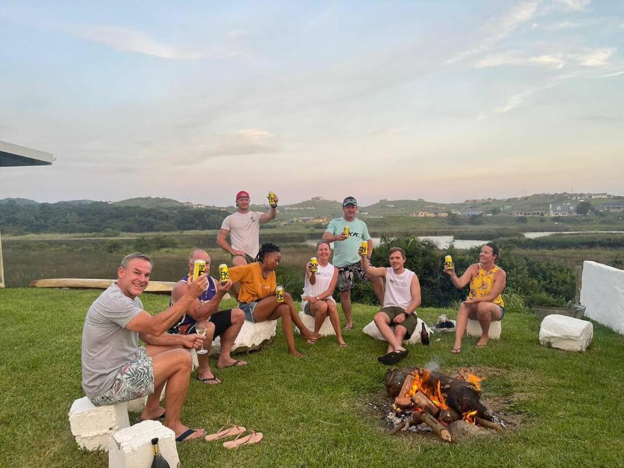 un grupo de personas sentadas alrededor de un fuego en Cheerful 10 sleeper cottage - Shower with a view. en Lusikisiki