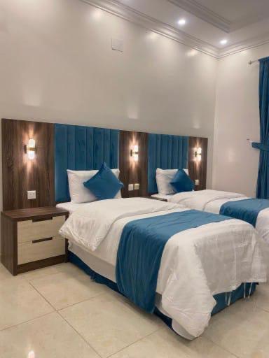 2 camas en un dormitorio con azul y blanco en فنون راحتي للشقق المخدومة, en Shariyah