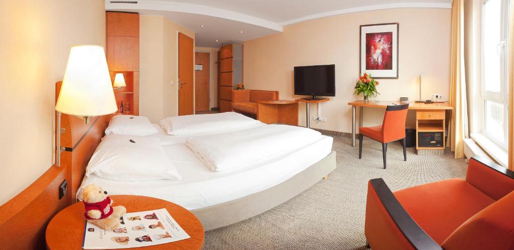ein Hotelzimmer mit einem großen weißen Bett und einem Tisch in der Unterkunft Best Western Premier Airporthotel Fontane BERlin in Schönefeld