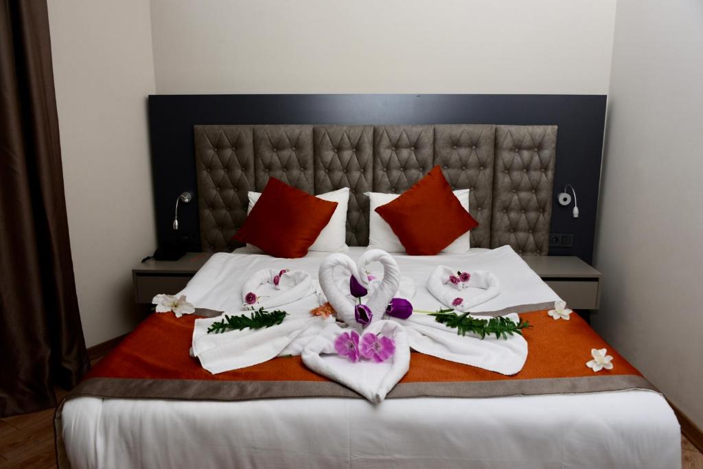 Una cama con toallas blancas y flores. en SiDE GOLDEN ROCK HOTEL&SPA en Side