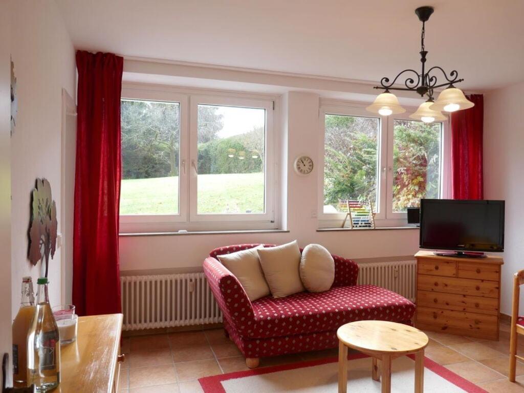 a living room with a red couch and windows at Holiday apartment Sonia on the lake in Bad Wiessee