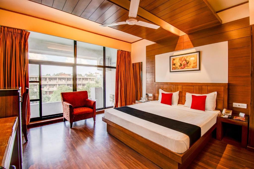 1 dormitorio con 1 cama y 1 silla roja en Hotel Broadway, en Chandīgarh