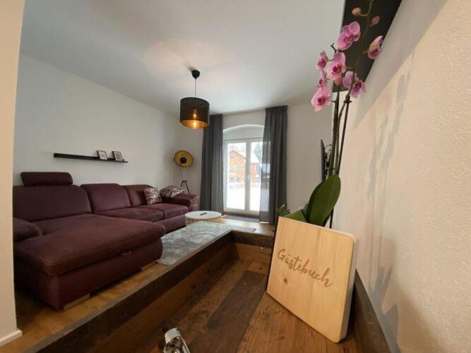 sala de estar con sofá marrón y cartel en Holiday home - Bimmelbahn 2, en Olbersdorf