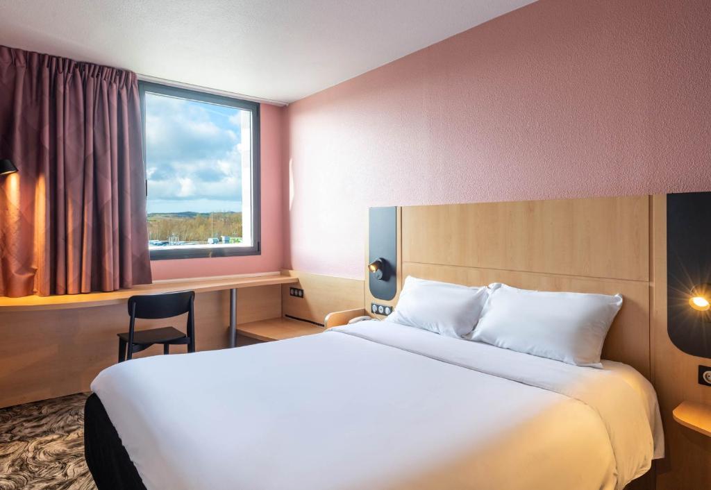 a hotel room with a large bed and a window at B&B HOTEL Calais Terminal Cité Europe 3 étoiles in Coquelles