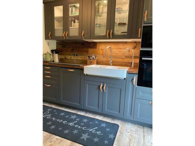 eine Küche mit blauen Schränken und einem Waschbecken in der Unterkunft Holiday home Waldhaus St Martin in Sankt Martin