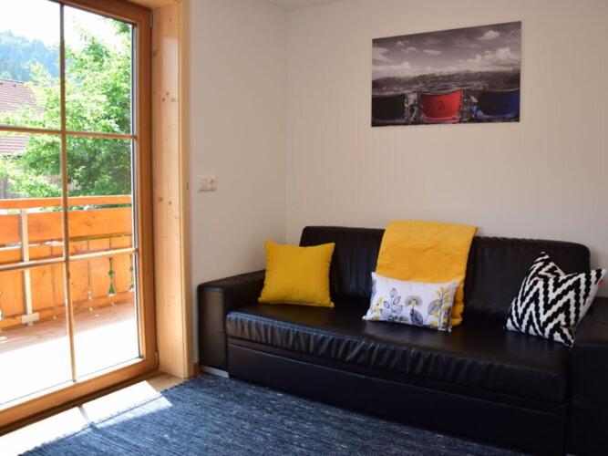ein schwarzes Sofa mit gelben Kissen im Wohnzimmer in der Unterkunft at Gallus - Wetterstein in Oberstaufen