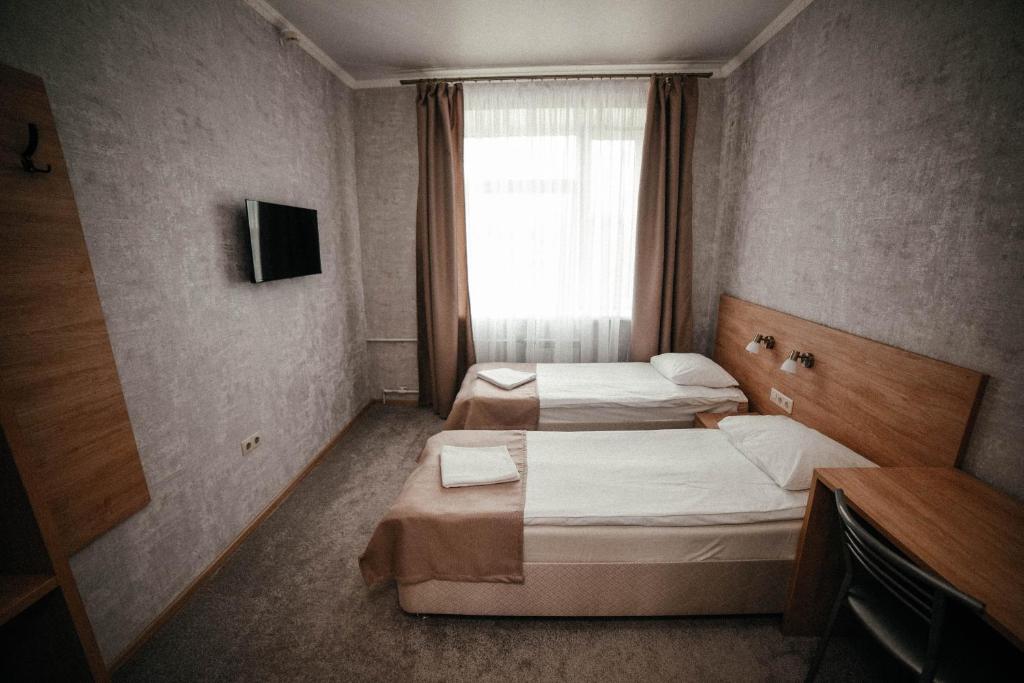 twee bedden in een kleine kamer met een raam bij Mini Hotel on Saydasheva in Kazan