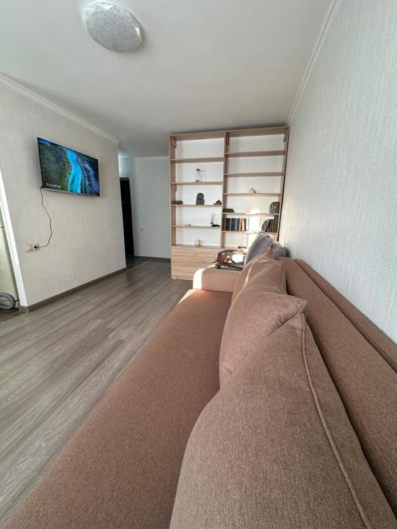 ein Wohnzimmer mit einem Sofa und einem TV an der Wand in der Unterkunft Квартира in Priozersk