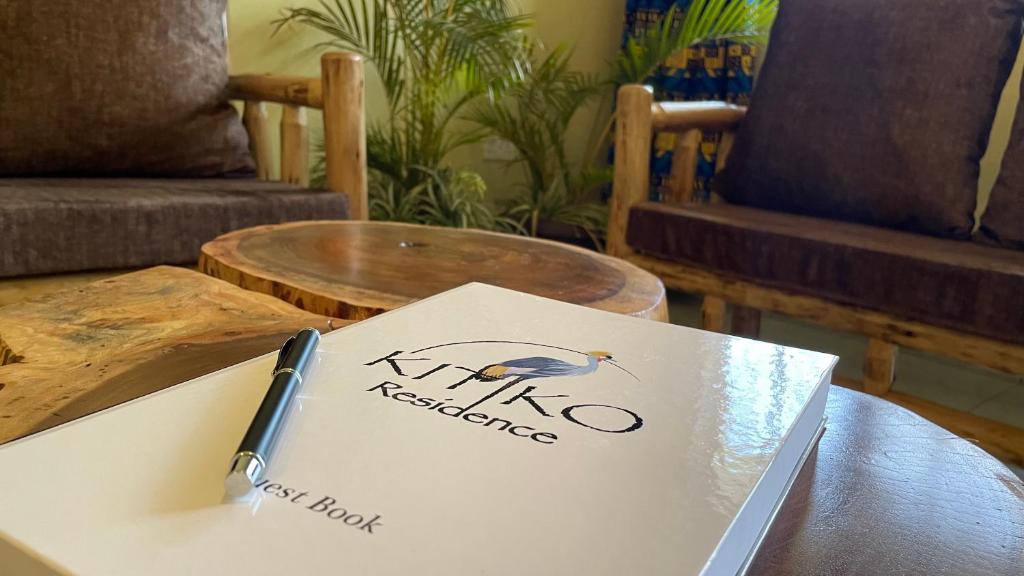 a book on a table with a pen on it at Kitiko residence Hotel in Entebbe