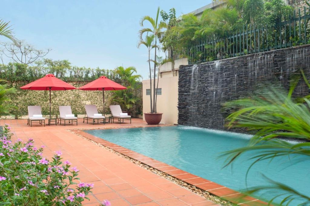 a swimming pool with chairs and umbrellas next to a building at Avani Hai Phong Harbour View Hotel in Hai Phong