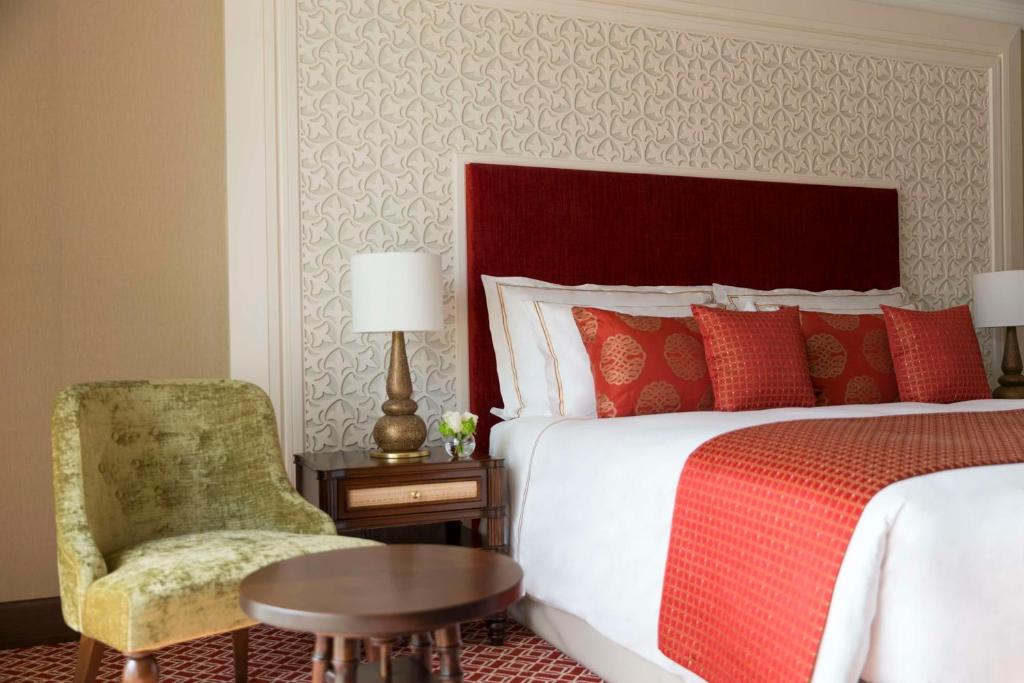فندق النجادة الدوحة من تيفولي في الدوحة: غرفة نوم بسرير وكرسي وطاولة