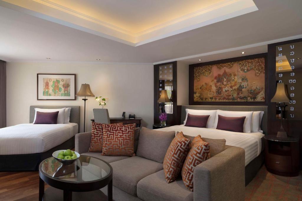 a hotel room with a couch and a bed at Anantara Riverside Bangkok Resort in Bangkok