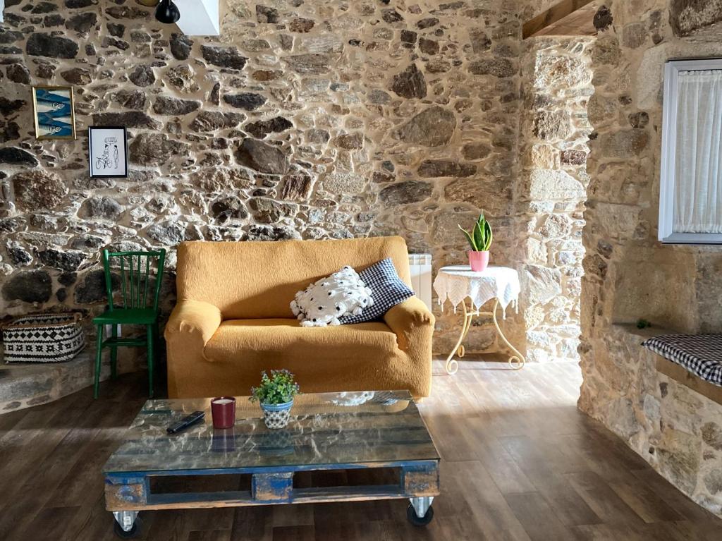 sala de estar con sofá y pared de piedra en Apartamento en Casa Oliveros, Razo, en A Coruña