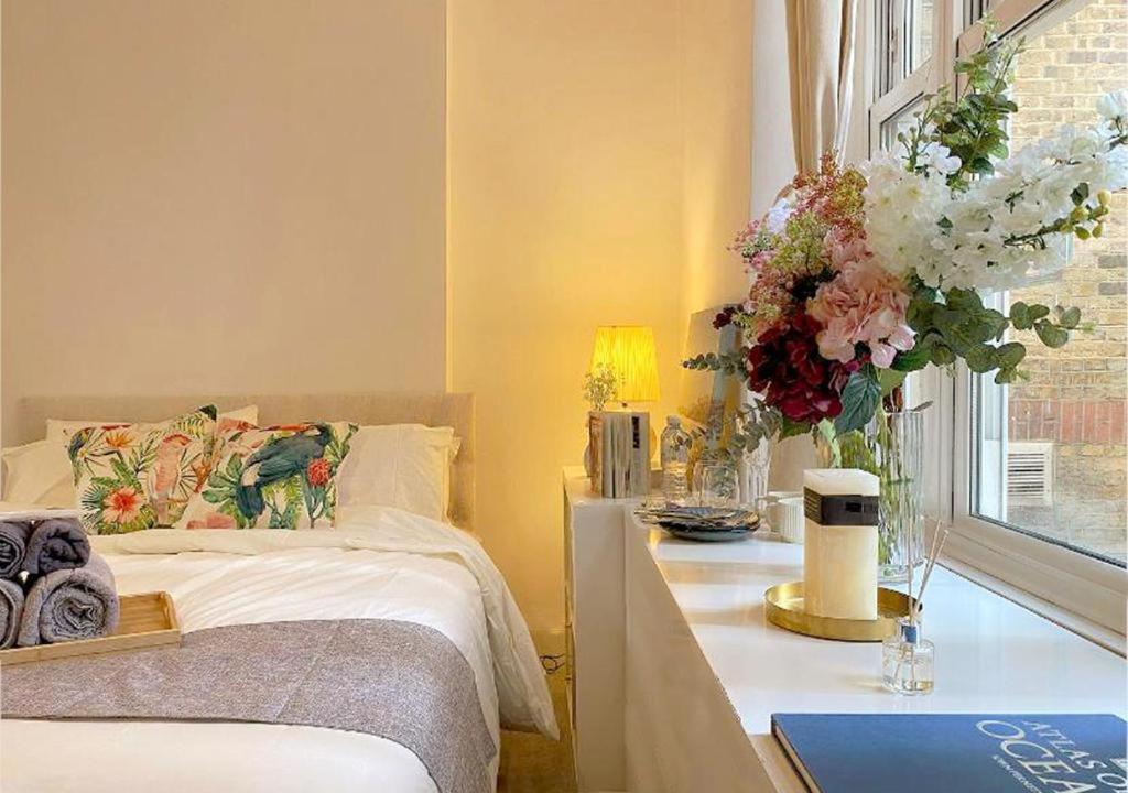 um quarto com uma cama e uma mesa com flores em Tower Bridge Borough Market London Bridge House em Londres