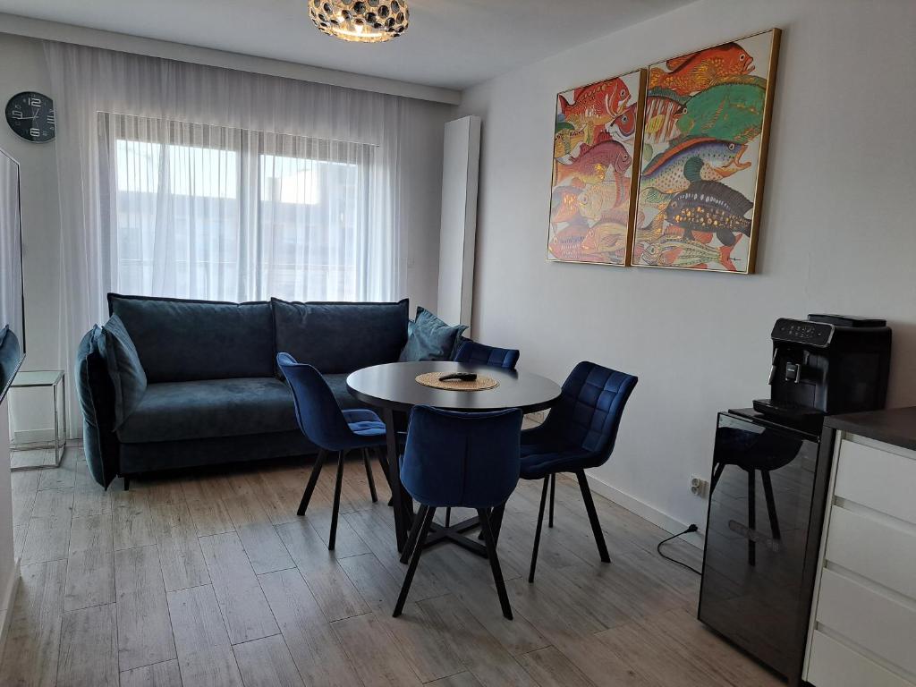 een woonkamer met een bank en een tafel en stoelen bij Gardenia Seaside Apartament 34 in Dziwnów