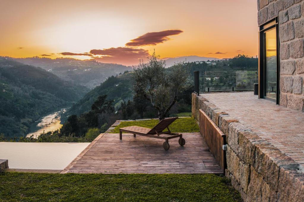 a bench sitting on a wooden deck with the sunset in the background at Javardo - Family House - Douro in Penha Longa