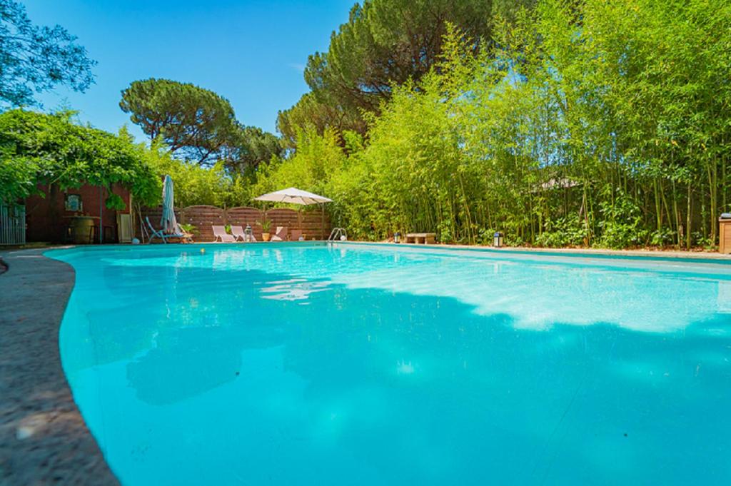 una gran piscina de agua azul en un patio en La Bastide des Pins en Castillon-du-Gard