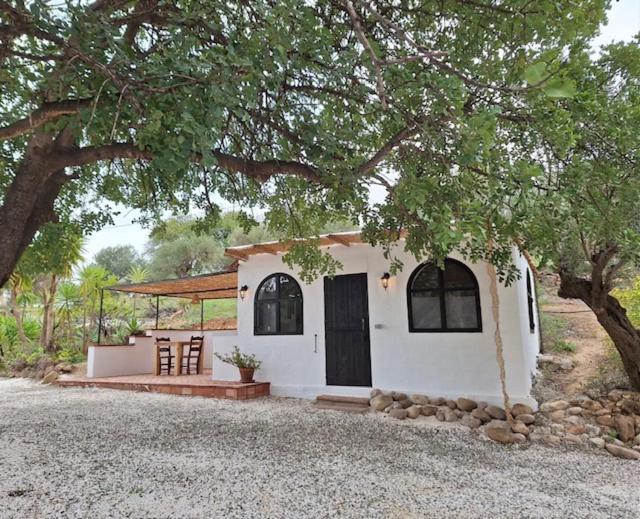 una pequeña casa blanca con un porche y un árbol en Casa del Sueño, en Álora