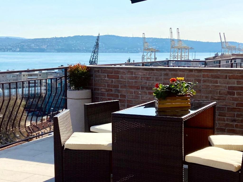 a table and chairs on a balcony with a view of the water at IL DANDY appartamento con parcheggio in Trieste
